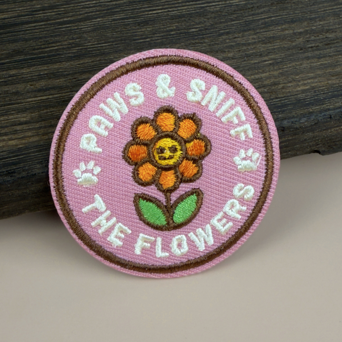 Circular patch with 'Paws & Sniff the Flowers' text and a flower illustration on a pink background.