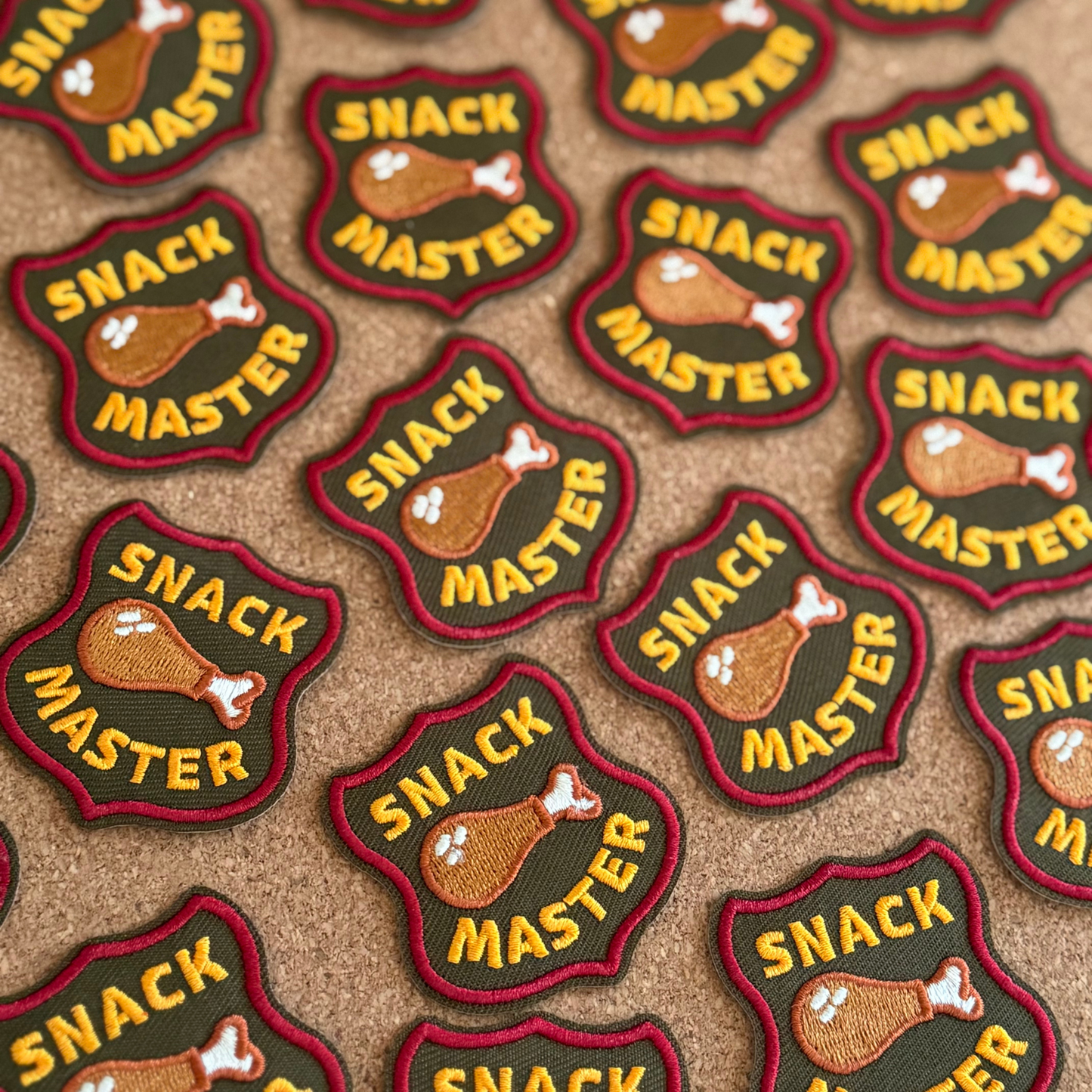 Pattern of 'Snack Master' patches with a turkey graphic on a brown background