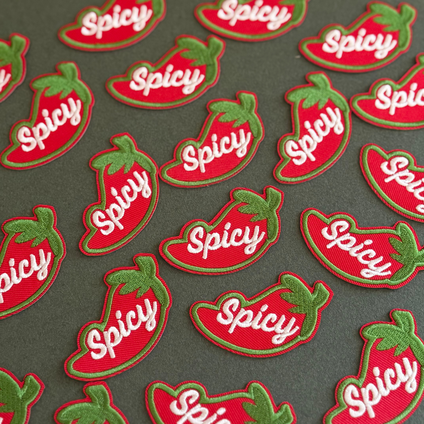 Pattern of red and green 'Spicy' chili pepper patches on a dark background