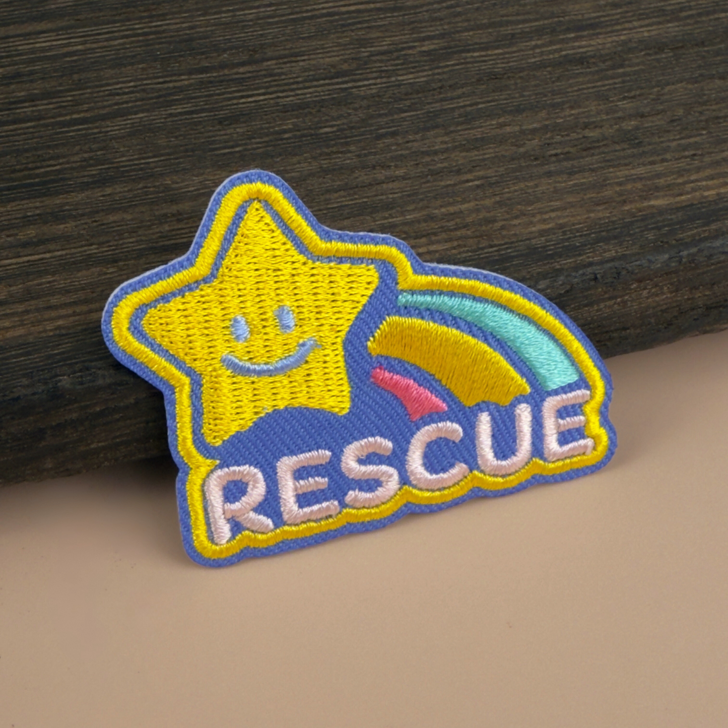Shooting star-shaped patch with 'RESCUE' text on a wooden surface