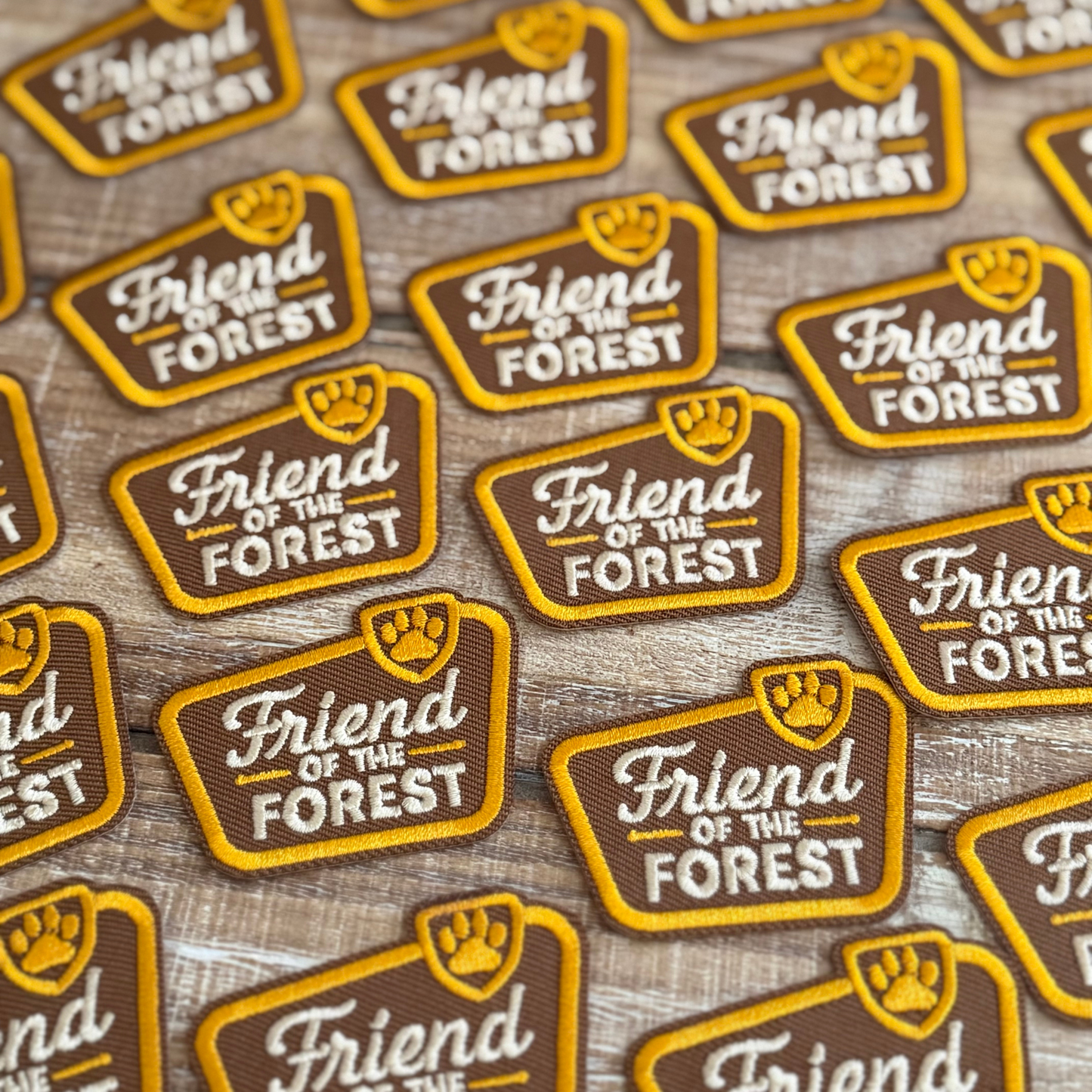 Multiple 'Friend of the Forest' patches on a wooden surface