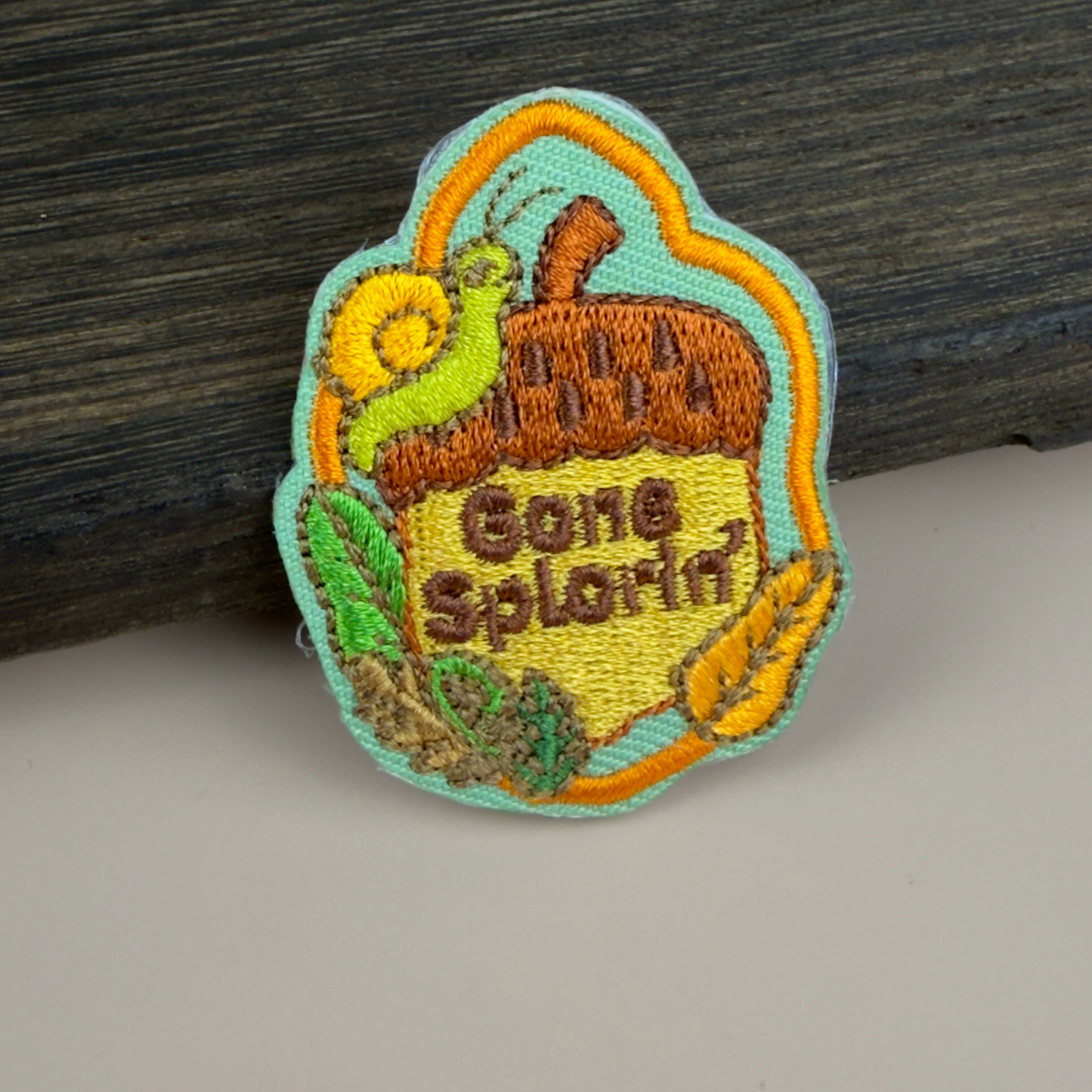 Embroidered patch with 'Gone Splorin'' text and nature-themed design on a wooden surface.