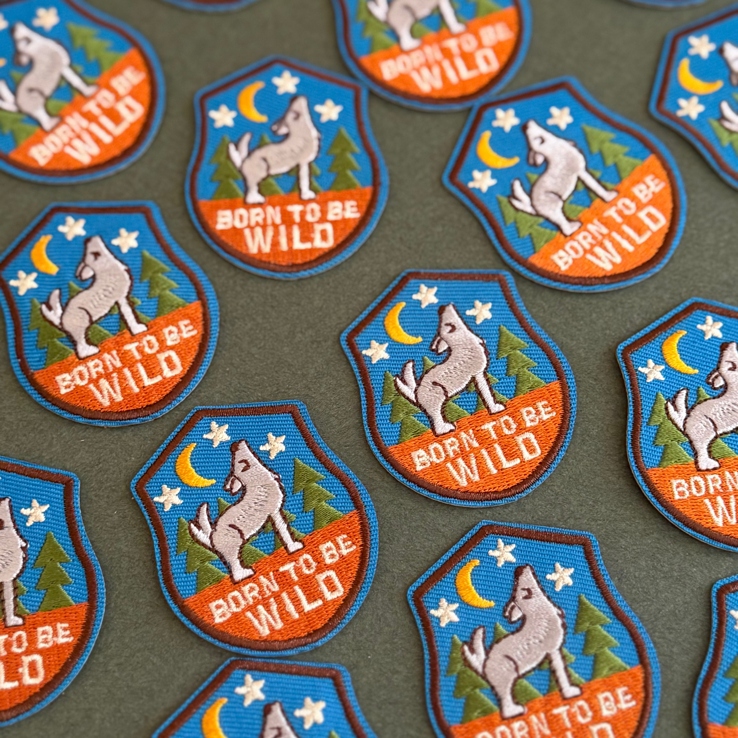 Collection of 'Born to be Wild' themed patches with wolf designs on a green background.