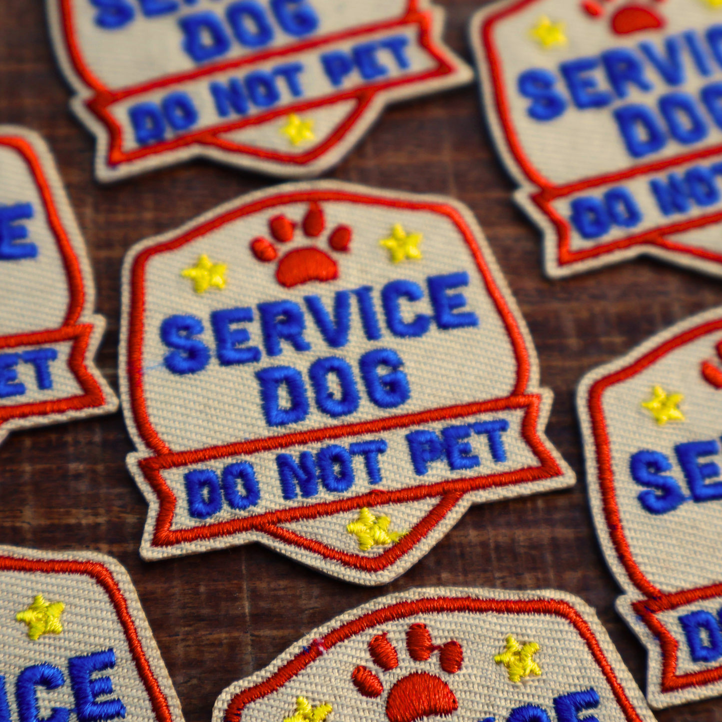 Service dog patches with 'Do Not Pet' text on a wooden surface
