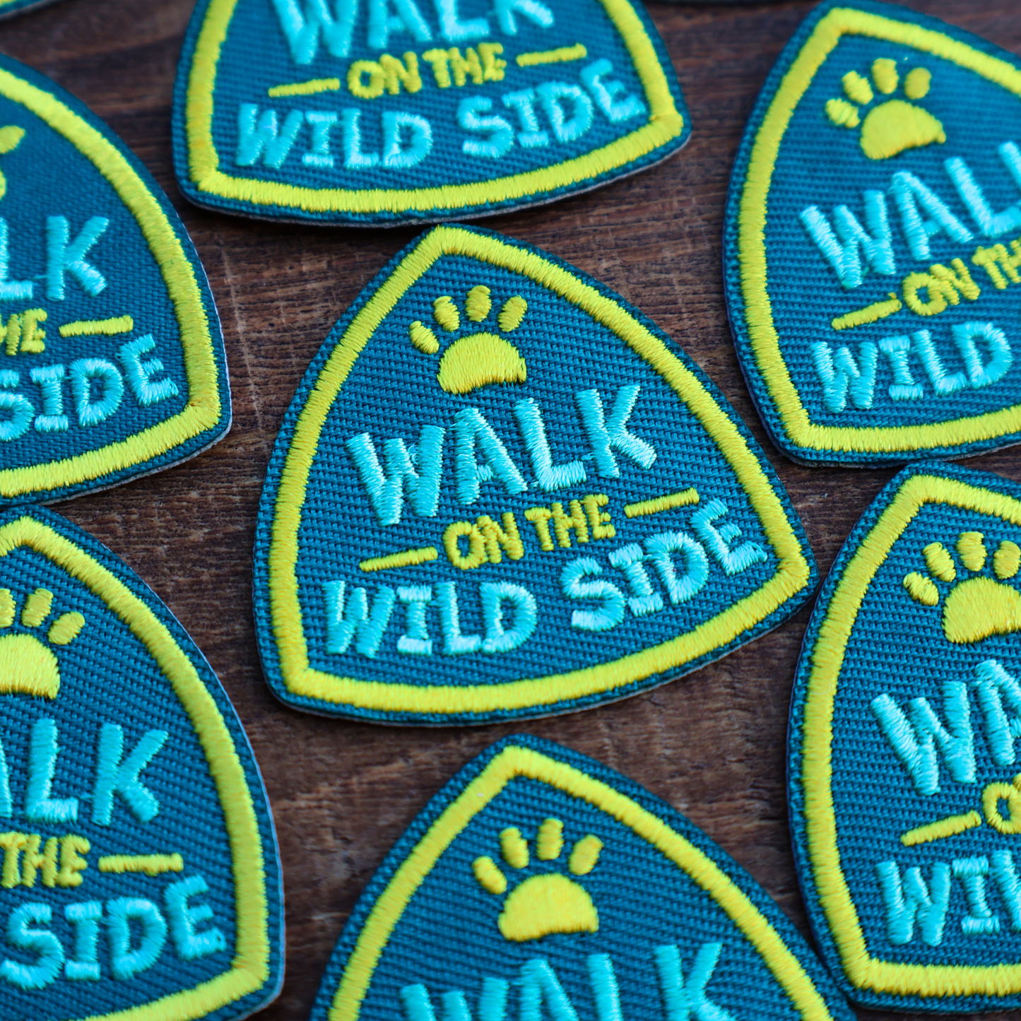Multiple 'Walk on the Wild Side' patches on a wooden surface