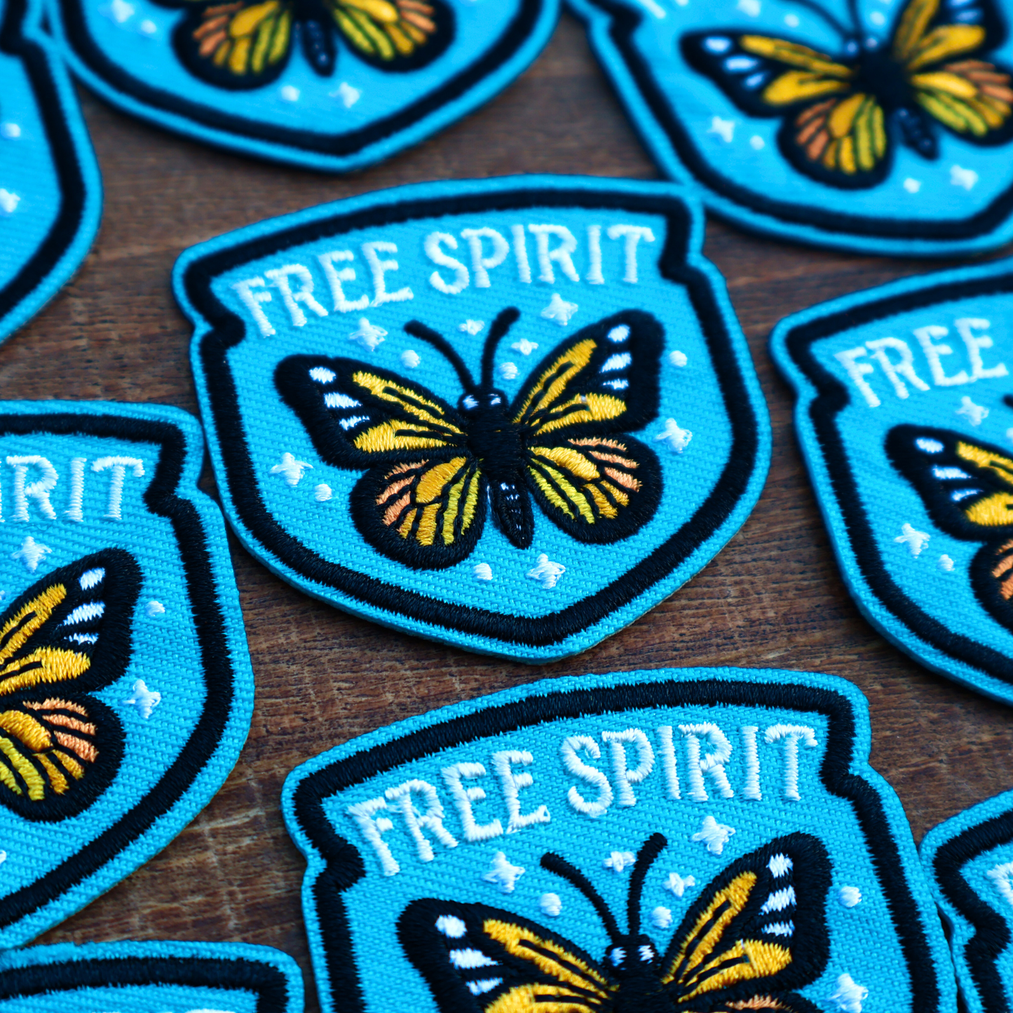 Embroidered iron-on patches with butterfly design and 'Free Spirit' text on a wooden surface