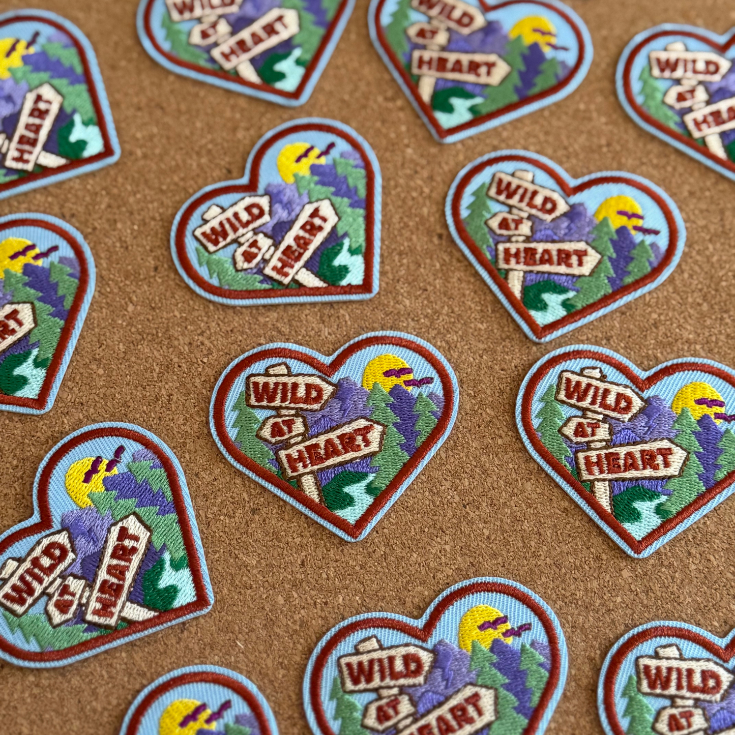 Heart-shaped patches with 'Wild at Heart' text and nature-themed design on a brown background