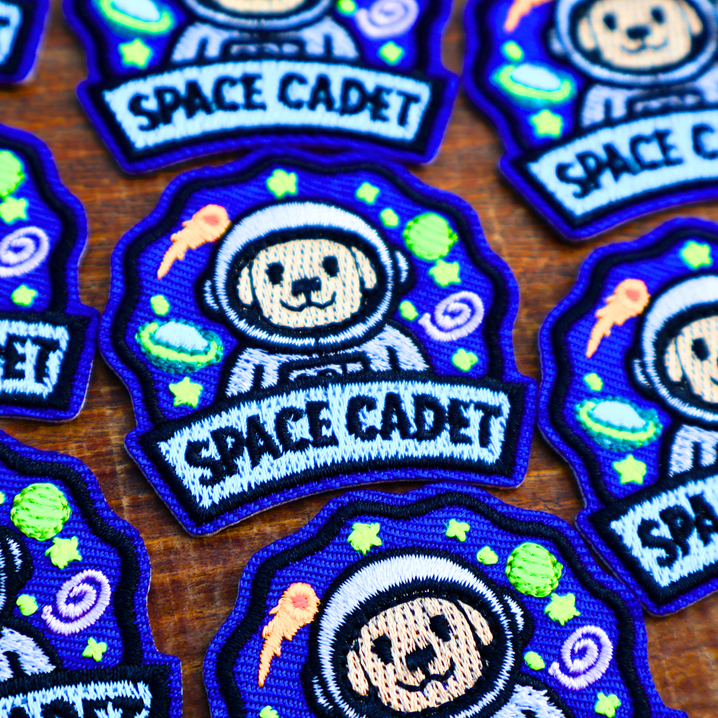 Embroidered patches with space-themed design and 'Space Cadet' text on a wooden surface.