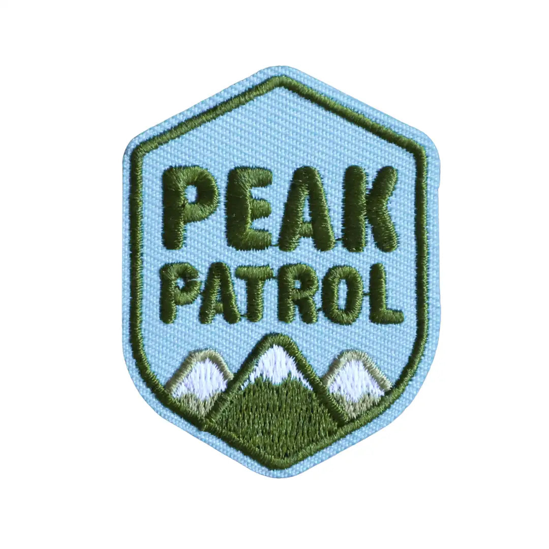 Iron-on patch with 'Peak Patrol' text and mountain design on a light blue background