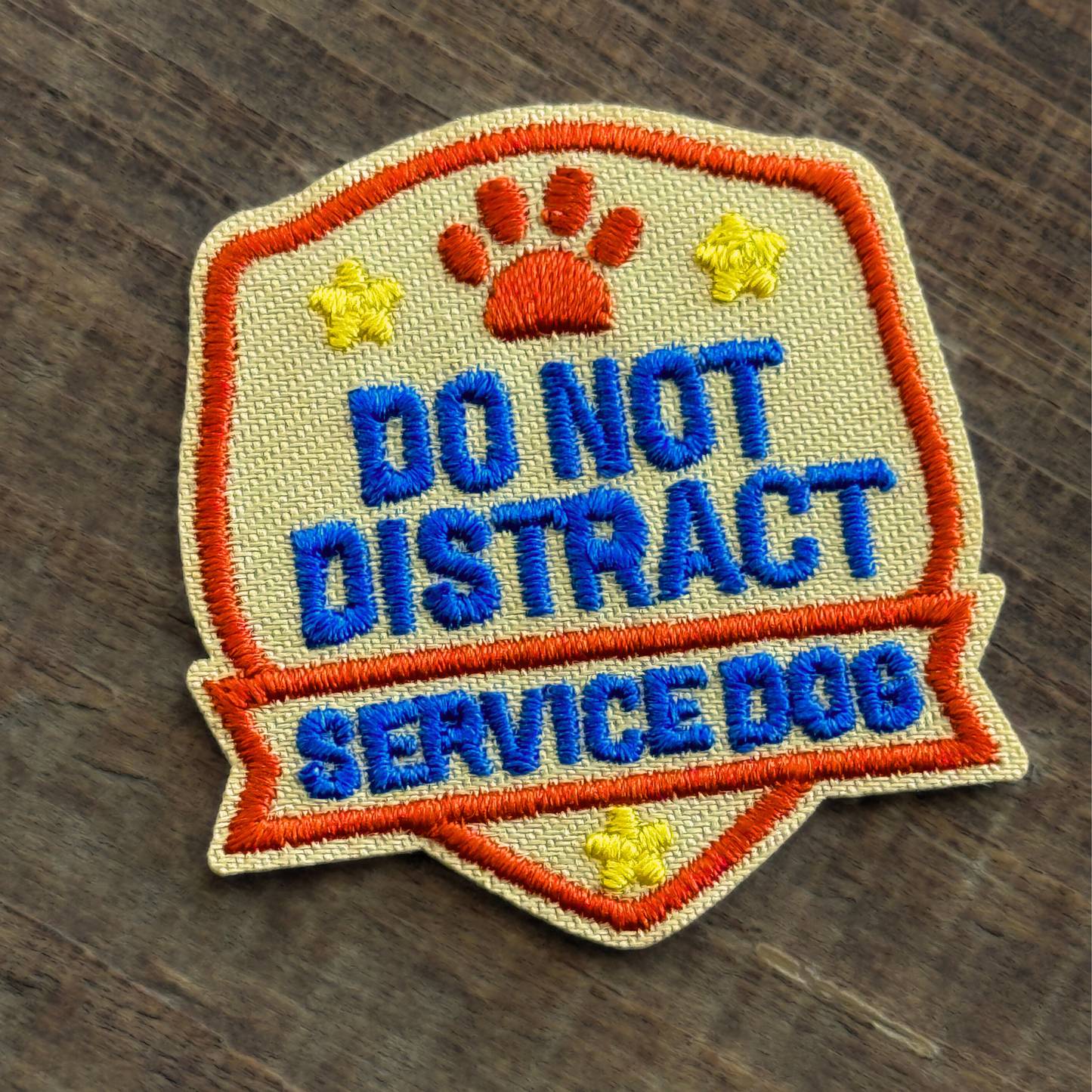 Embroidered iron-on patch with 'Do Not Distract Service Dog' text on a wooden surface