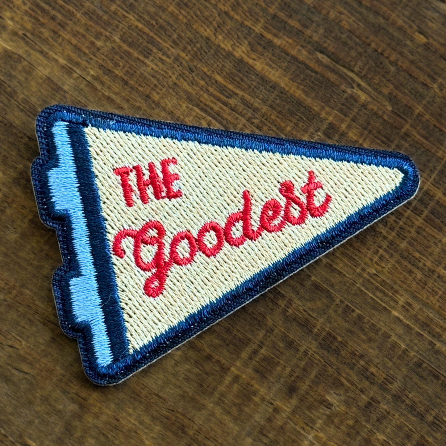Embroidered iron-on patch with 'The Goodest' text on a wooden surface