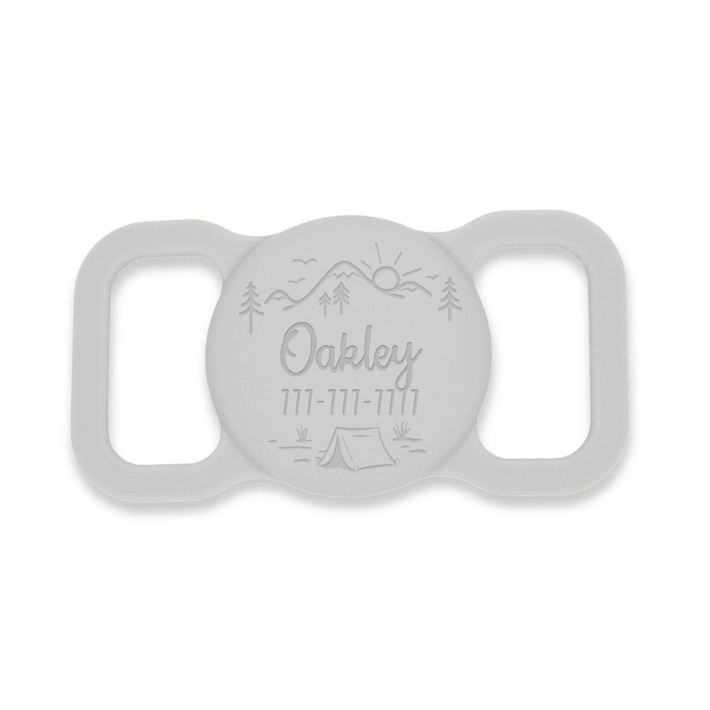 Grey silicone AirTag holder with an outdoors landscape design, featuring a mountain with a sunrise. Pet's name and phone # are custom engraved.